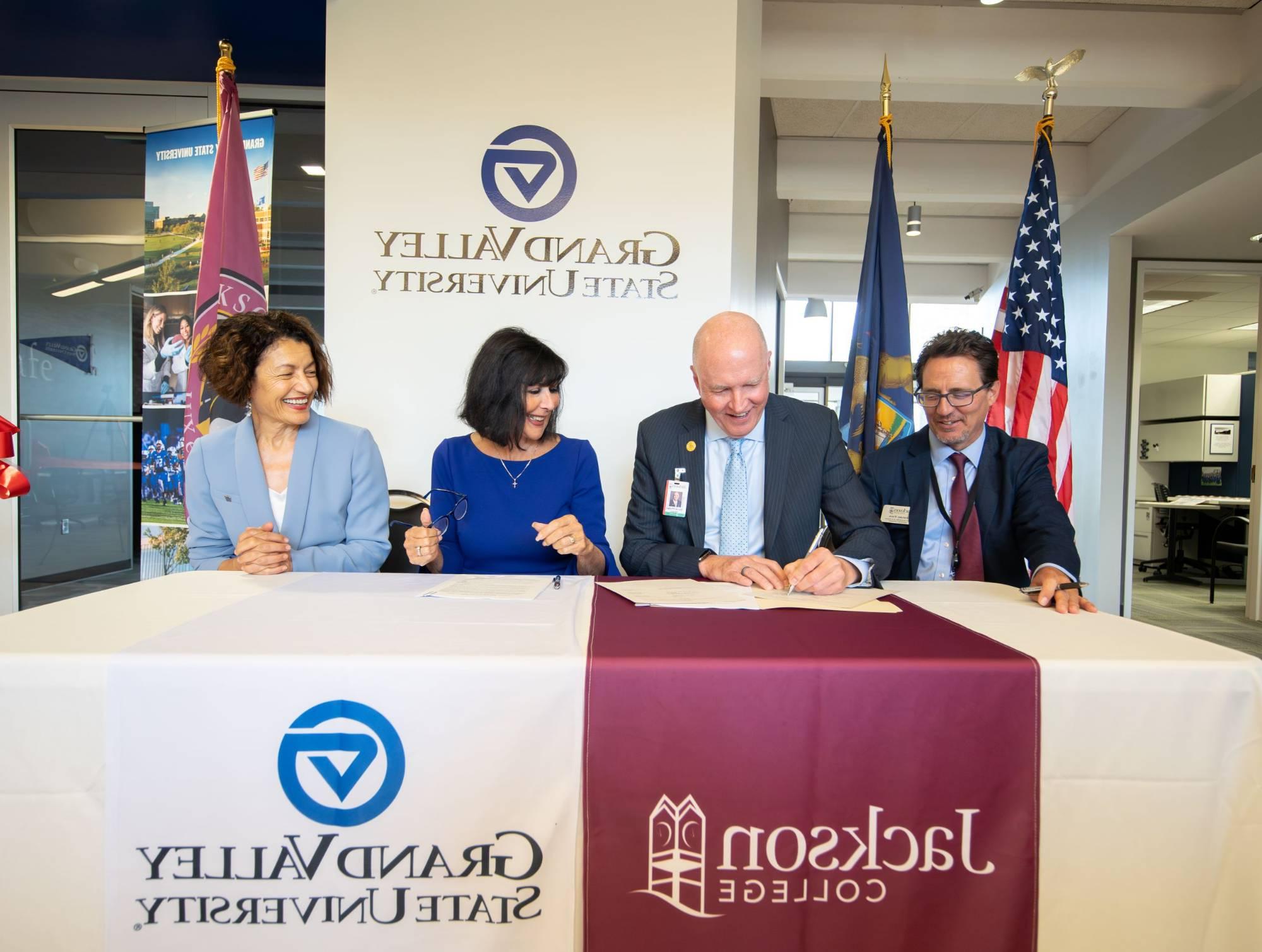 GVSU and Jackson College leaders sitting at a table signing documents